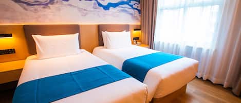 A hotel room with two beds, a marble wall mural, a large window with curtains, and a wooden floor.