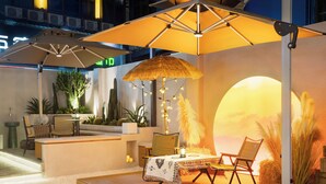 A cozy indoor seating area with a table, chairs, and a large umbrella providing shade. - NAIVE L Executive Apartments Coast City (Shenzhen)