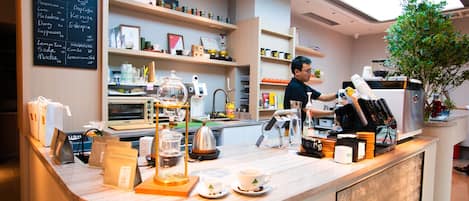 Una cafetería moderna con mostrador, estantes con diversos productos y un menú en la pared.