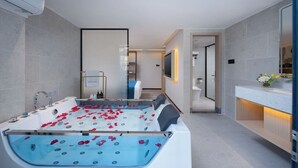 A modern bathroom with a large bathtub, a separate shower area, and a vanity with a mirror. - NAIVE L Executive Apartments Coast City (Shenzhen)