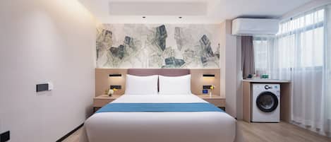 Habitación de hotel moderna con una cama grande, lavadora y vistas a la ciudad a través de amplios ventanales.