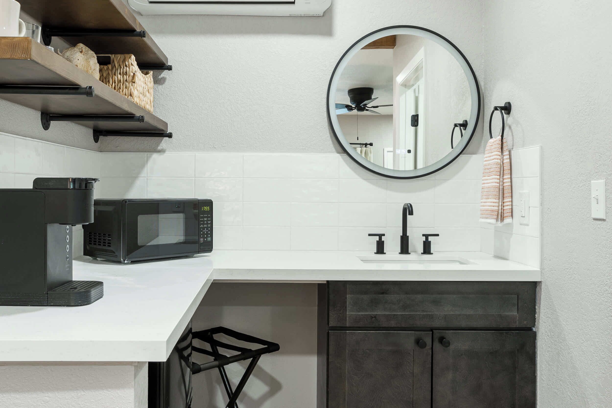 A modern kitchen with a white countertop, black microwave, and dark cabinets.