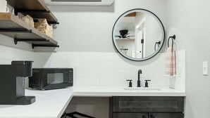 A modern kitchen with a white countertop, black microwave, and dark cabinets. - Moro RM3 Sequoia Motel- AC, Pool, WiFi, 10min SNP (Three Rivers)