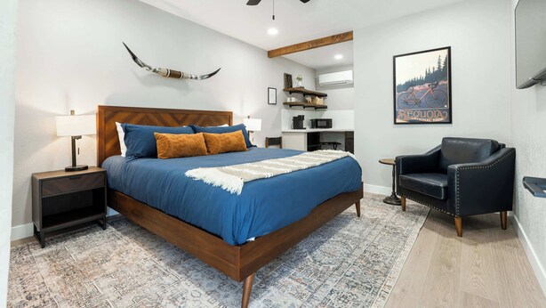 A modern bedroom with a wooden bed, a ceiling fan, a mounted TV, and a mounted artwork of a mountain bike. - Moro RM3 Sequoia Motel- AC, Pool, WiFi, 10min SNP (Three Rivers)