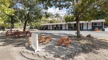 Un motel con mesas al aire libre, un espacio cubierto y aparcamiento.