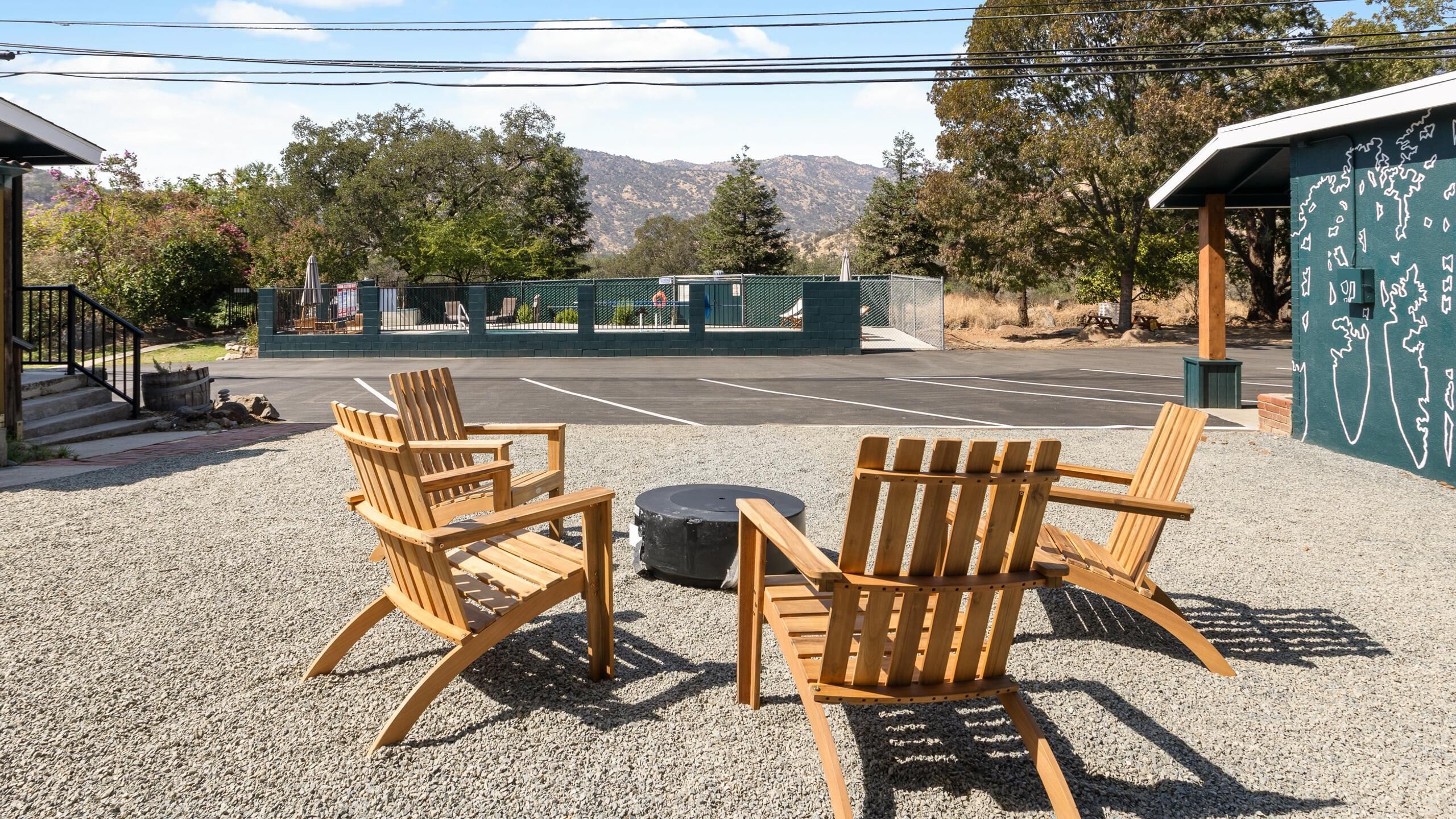 Eine gepflasterte Terrasse mit Holz-Adirondack-Stühlen und einer Feuerstelle.