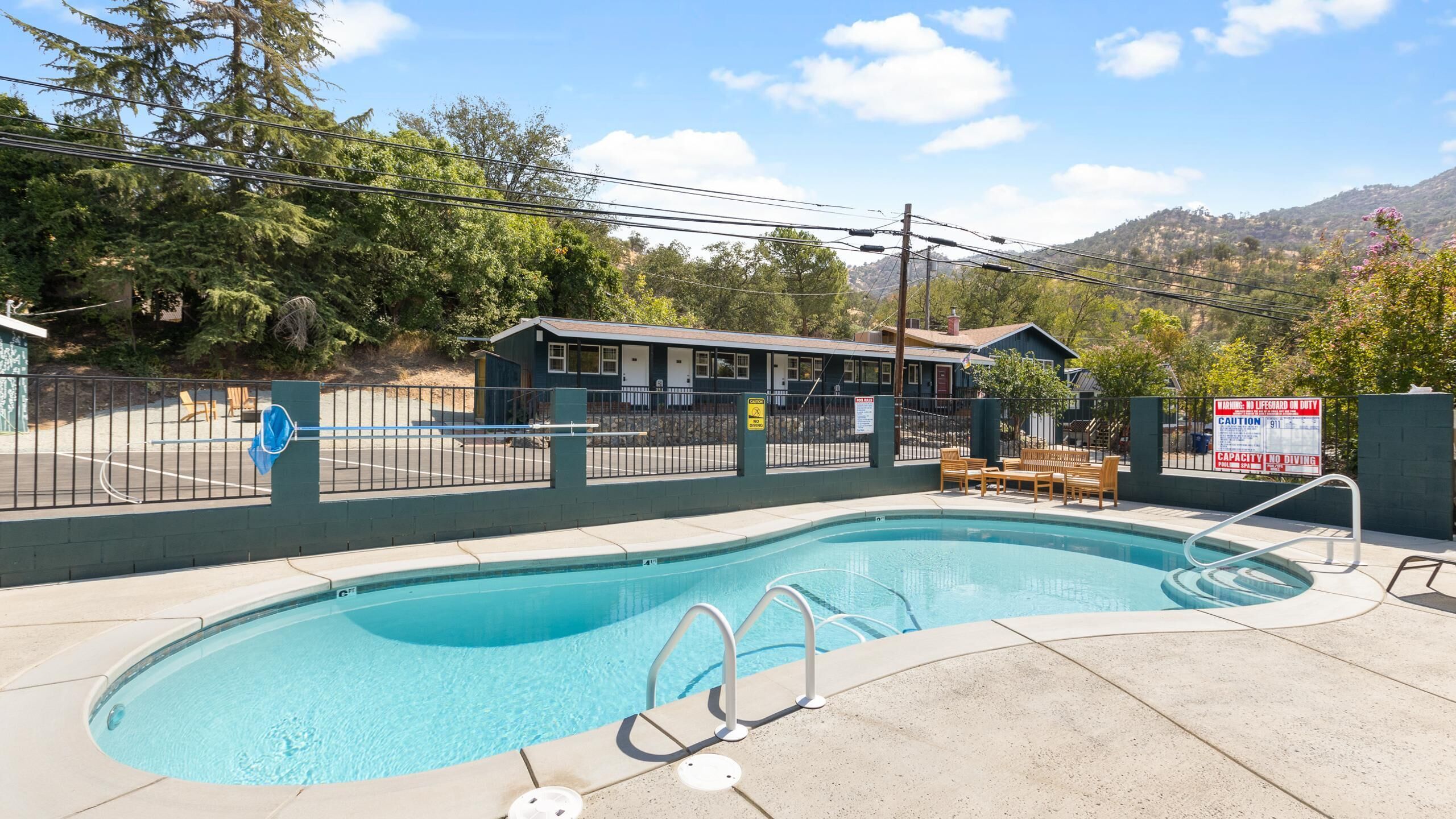 Ein Swimmingpool mit Rettungsschwimmerstation, überdachtem Sitzbereich und Bergblick.