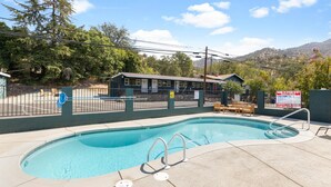 A swimming pool with a lifeguard station, a covered seating area, and a mountain backdrop. - The Whitney Room 7 Sequoia Motel - Mins to Park! (Three Rivers)