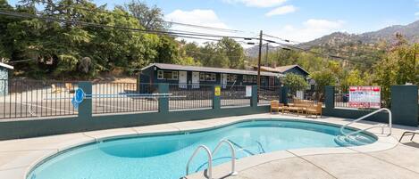 A swimming pool with a lifeguard station, a covered seating area, and a mountain backdrop.