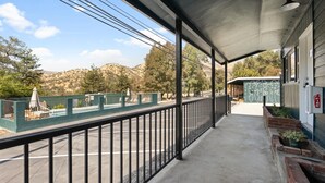 Un espace extérieur abrité, doté d’un sol en béton, d’une rambarde en métal et offrant une vue sur un paysage vallonné.