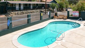 A swimming pool with a metal fence, a lifeguard chair, and a sign warning of no lifeguard on duty.