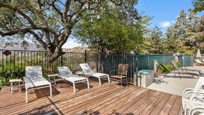 Eine Holzterrasse mit weißen Liegestühlen und einem Metallzaun.