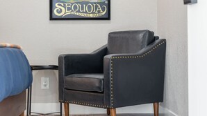 Ein Zimmer mit einem schwarzen Ledersessel, einem Bett mit blauer Bettdecke, einem gerahmten Bild von Sequoia National Park und einem gemusterten Teppich.