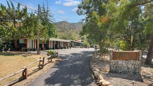 A motel with a stone sign, paved driveway, and surrounding trees.