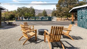 A gravel patio with wooden Adirondack chairs and a round table.