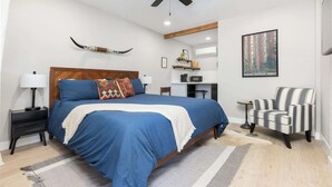 A bedroom with a large bed, a ceiling fan, a chair, and a poster on the wall. - The Rae Sequoia Motel RM5 (Three Rivers)