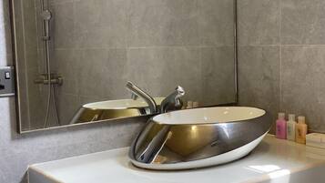 A bathroom with a large mirror, two sinks, and a shower.