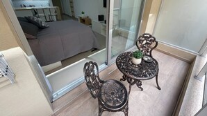 Een moderne slaapkamer met een groot bed, een kleine tafel met een plant en een stoel.