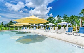 A swimming pool with lounge chairs and umbrellas, surrounded by greenery.
