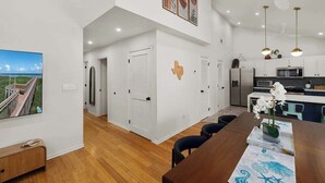 Una cocina moderna con alacenas blancas, un microondas y una zona de comedor con una mesa y sillas de madera.