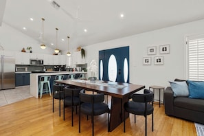 Una cocina moderna con armarios blancos, un refrigerador de acero inoxidable y una isla central con taburetes de bar.