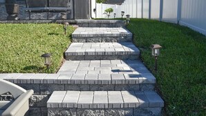 A set of stone steps leading to a modern house with a covered patio area. - New Canal Access Pool Home w/Outdoor Oasis/Kayaks (Cape Coral)