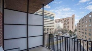 Un balcon donnant sur les bâtiments environnants et un espace de stationnement.