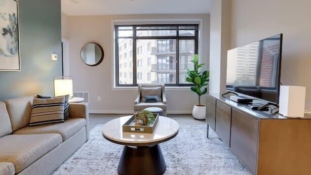 Un salon moderne avec un canapé, une table basse, un téléviseur et une grande fenêtre.