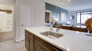 Een moderne keuken met een groot eiland, een inbouwgootsteen en uitzicht op de eethoek.