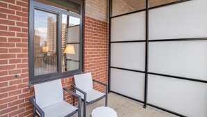 Een balkon met twee stoelen, een raam en een uitrolbaar zonnescherm.