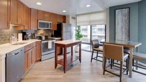 A modern kitchen with wooden cabinets, stainless steel appliances, and a dining area with a glass table and chairs.