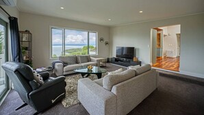 Amplia sala de estar con un gran ventanal, un televisor de pantalla plana y un espacio de descanso confortable.