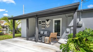 A modern house with a covered porch, a small table, and a chair.