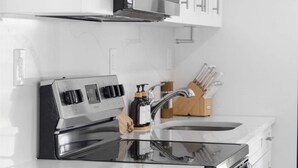 Una cocina moderna con electrodomésticos de acero inoxidable, muebles blancos y un portalapices de madera.