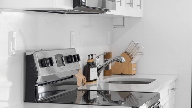 A modern kitchen with stainless steel appliances, white cabinetry, and a wooden utensil holder.