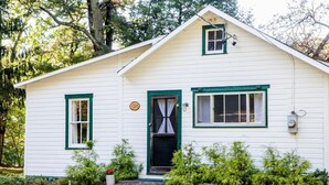 A white house with green trim, a front door with a curtain, and a mailbox. - Esopus Creek Cottage (Saugerties)