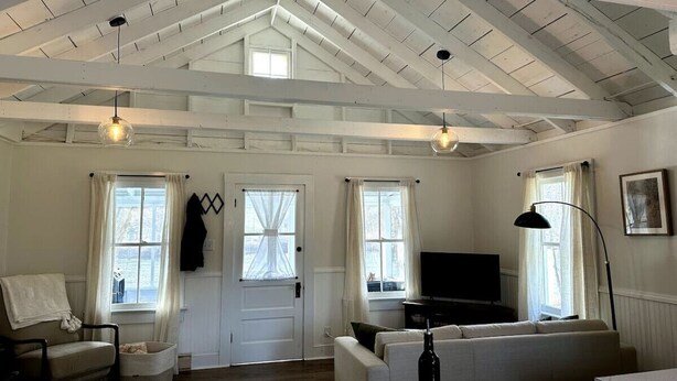 A spacious living room with a high ceiling, a television, a sofa, and a chair. - Esopus Creek Cottage (Saugerties)