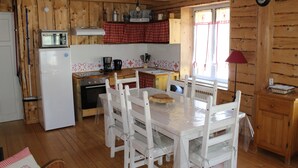 Een houten chalet met een keukenhoek, inclusief een koelkast, oven en houten keukenkastjes.
