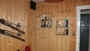 Een kamer met houten lambrisering, een bed, een rode lamp en twee boekenplanken vol boeken.