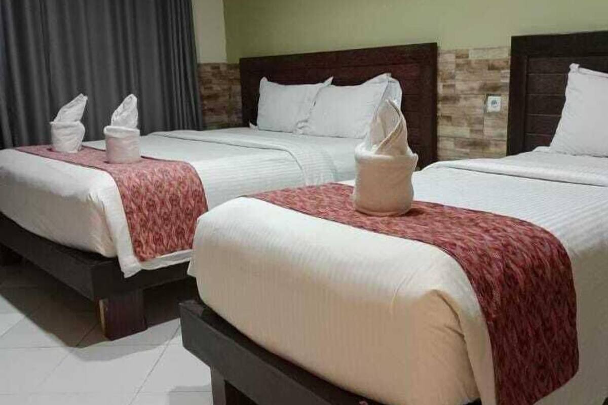 A hotel room with two beds, each with a pillow and a tissue.