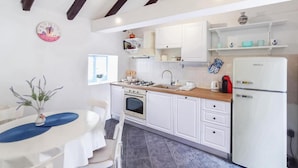 A kitchen with white cabinets, a stove, sink, and a refrigerator. - Didini Dvori in Kru evo (Obrovac)