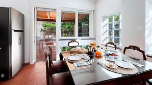 Una cuina moderna amb taula de dinar a punt per l'esmorzar, un refrigerador i grans finestres que donen vistes a l'exterior.