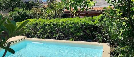 A swimming pool surrounded by lush greenery and residential buildings.