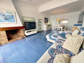 A living room with a TV, fireplace, sofa, and dining area.
