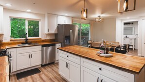 A modern kitchen with white cabinets, a wooden countertop, and stainless steel appliances.