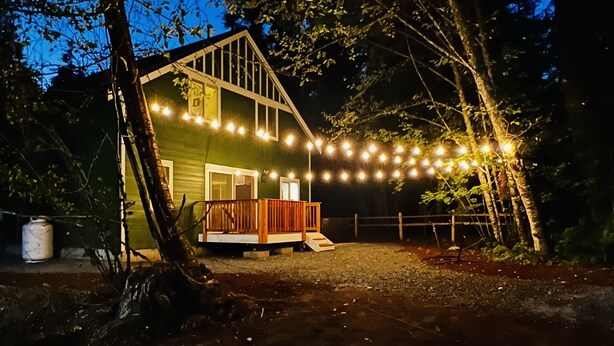 A house with a deck, string lights, and a fire pit.