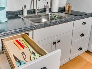 Eine Küche mit Spüle, einer Kaffeemaschine und einer Schublade voller Küchenutensilien.