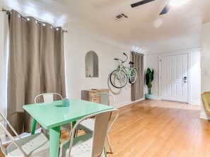 Une pièce comprenant une table à manger, des chaises, un vélo fixé au mur, une porte et une plante en pot.