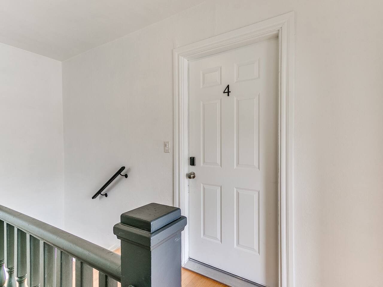 A white door with the number 4, a metal handrail, and a trash can with a lid.