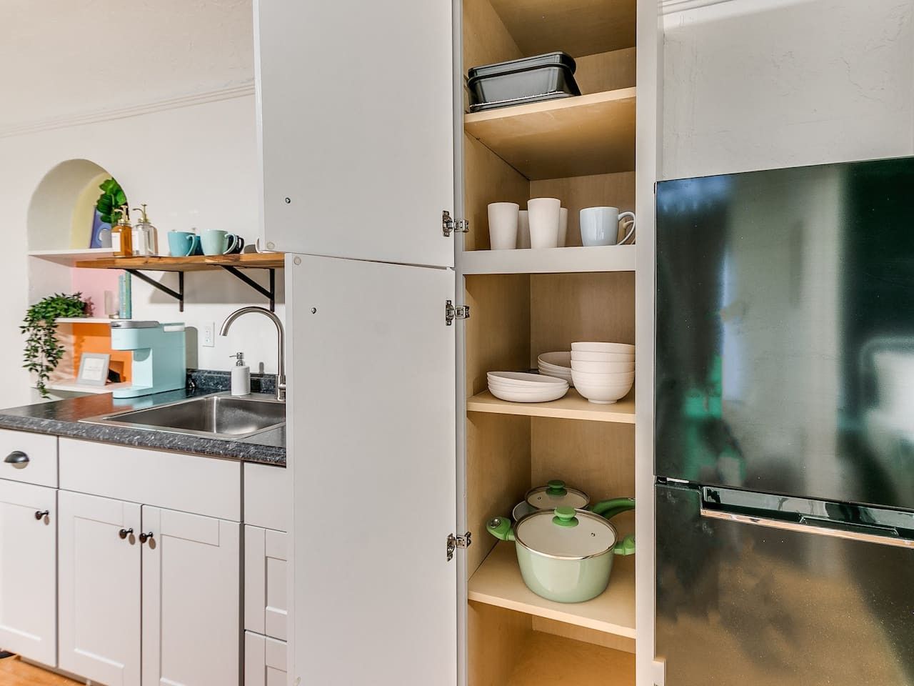 A kitchen with white cabinets, a stainless steel refrigerator, and a countertop with a sink.